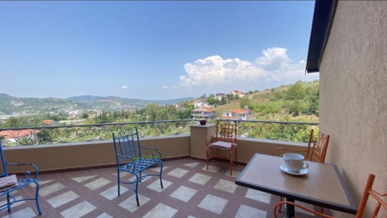 Coffee on the balcony, village rooftops below.