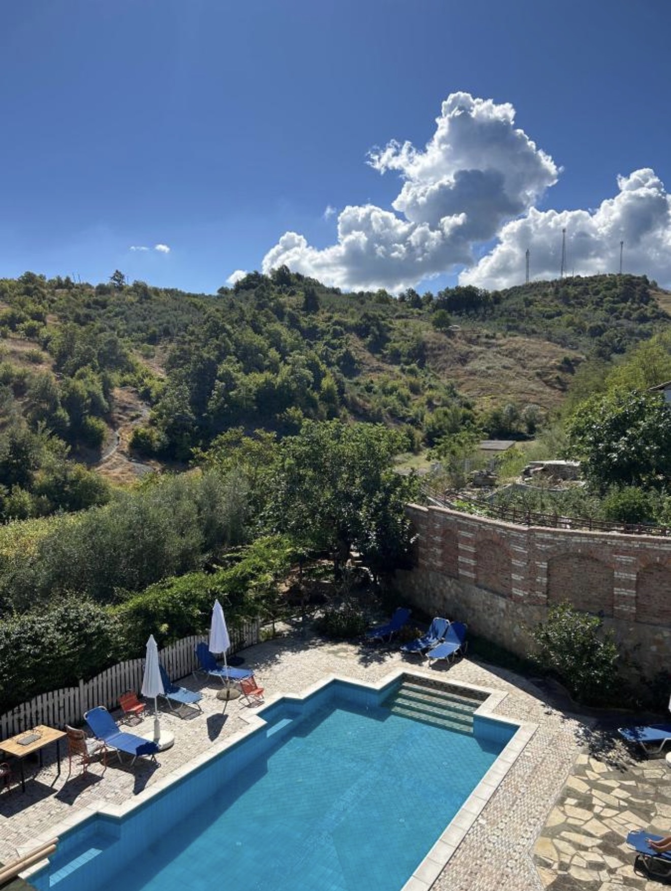The pool and garden from above, hillside on the horizon.